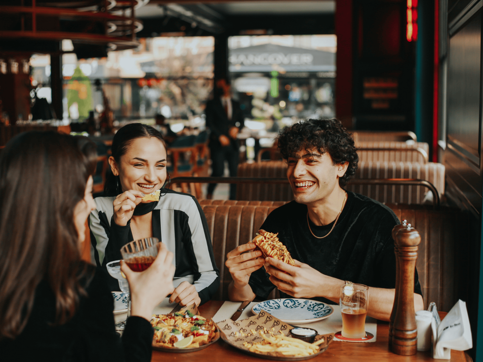 A group of friends in a dining booth with a diverse set of freshly made dishes